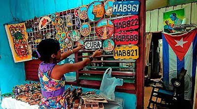 Mujer en tienda pequeña pintada de turquesa brillante con productos artesanales a la venta