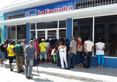 People queuing with clothes of different colors to enter a warehouse in Cuba