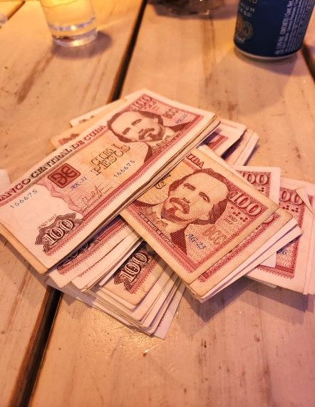 billetes cubanos de cien pesos amontonados en una mesa