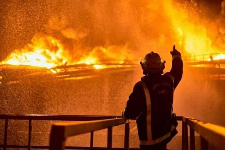 silueta de un bombero señalando a un incendio enorme