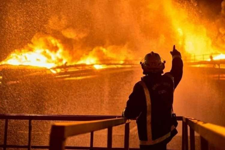 silhouette of a firefighter pointing to an enormous blaze