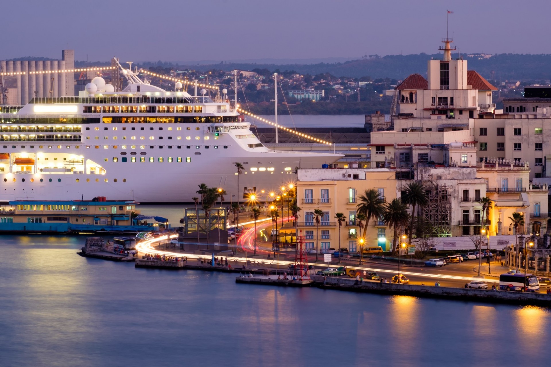 Crucero blanco iluminado al anochecer en el puerto de La Habana