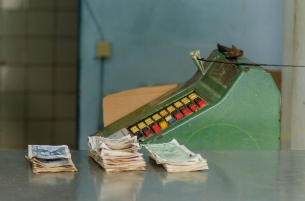 dinero cubano en frente de una caja registradora verde