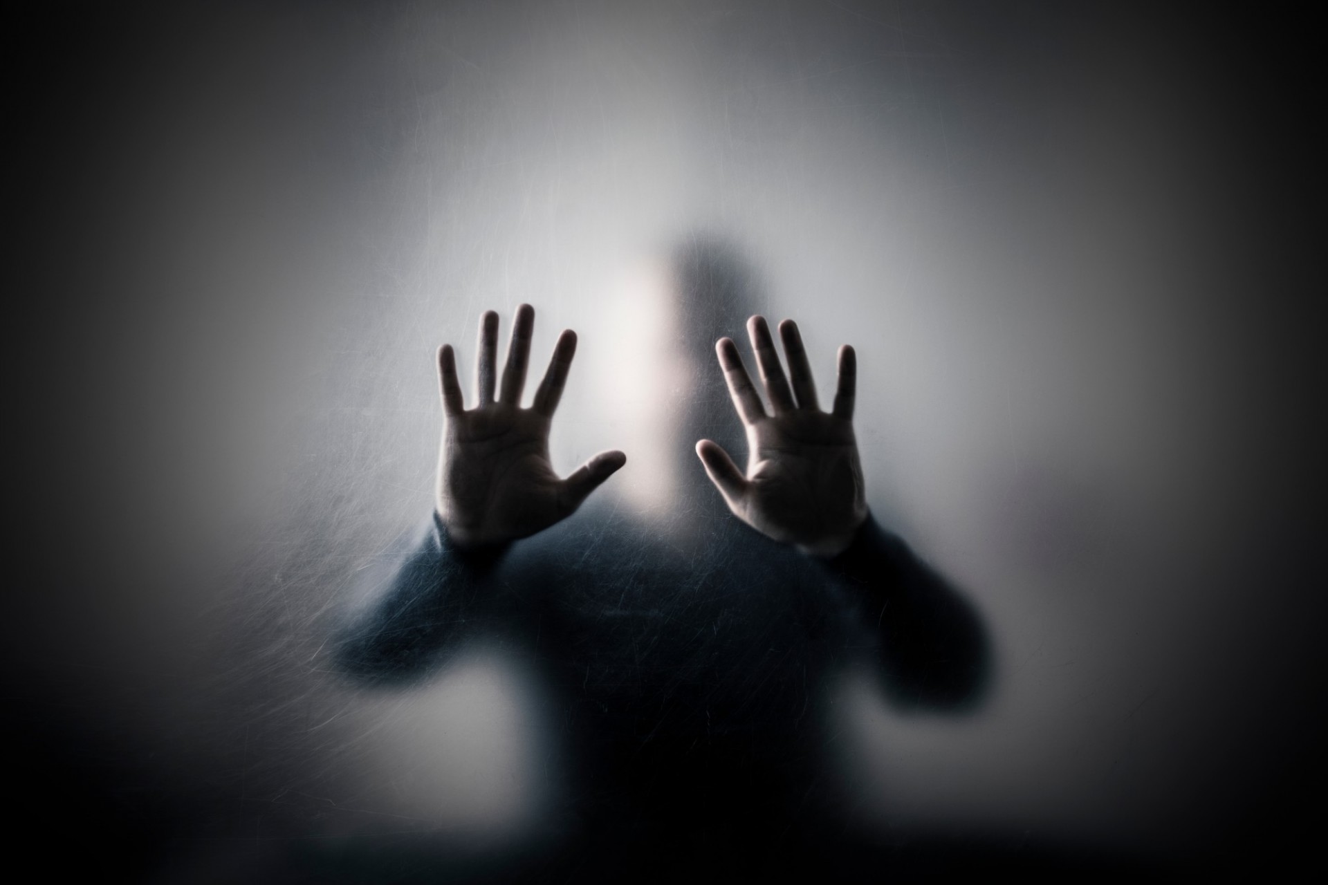 Jakub Krechowicz/stockadobe.com silueta de hombre con manos alzadas detrás de vidrio rallado