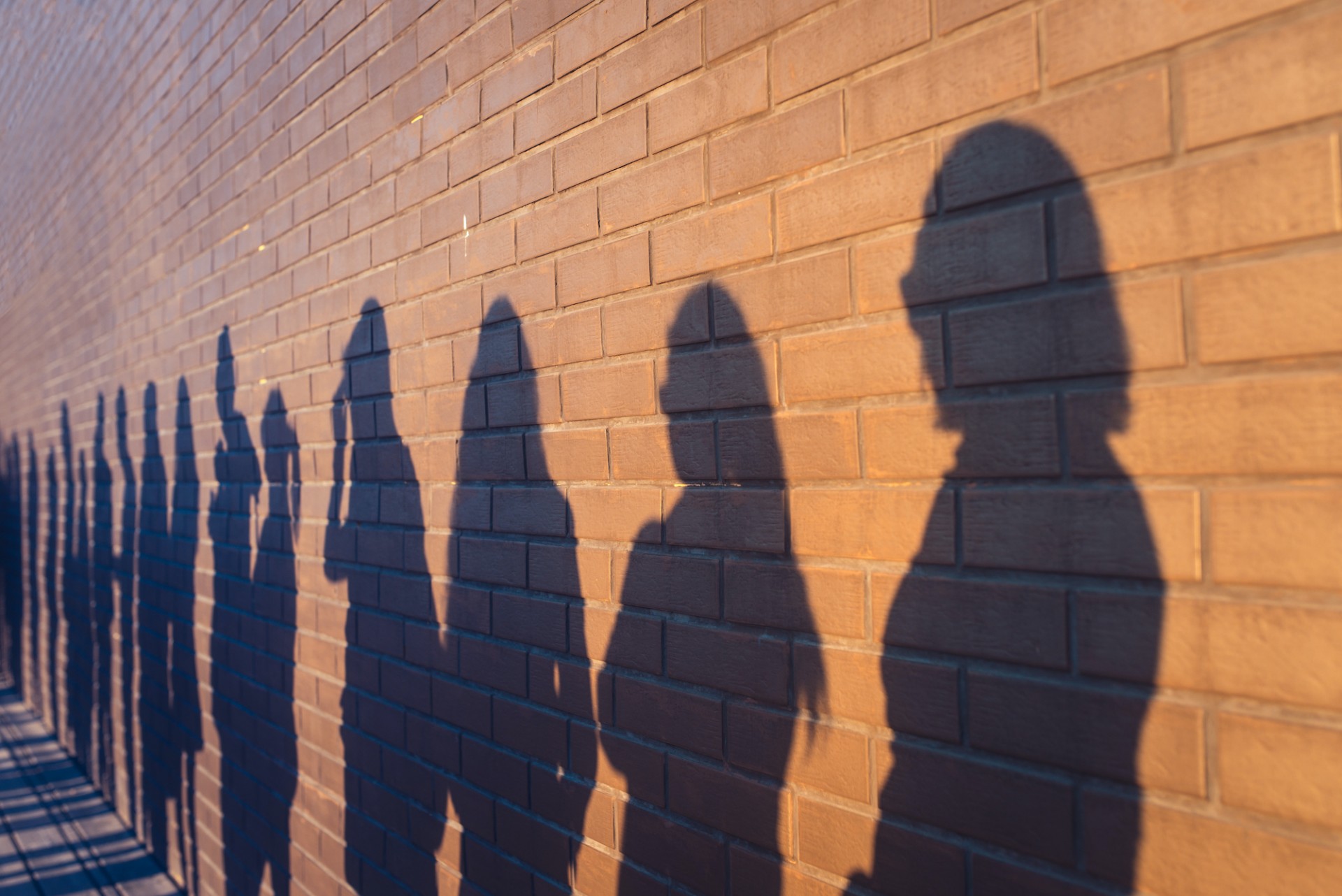 human shadows against a brick wall