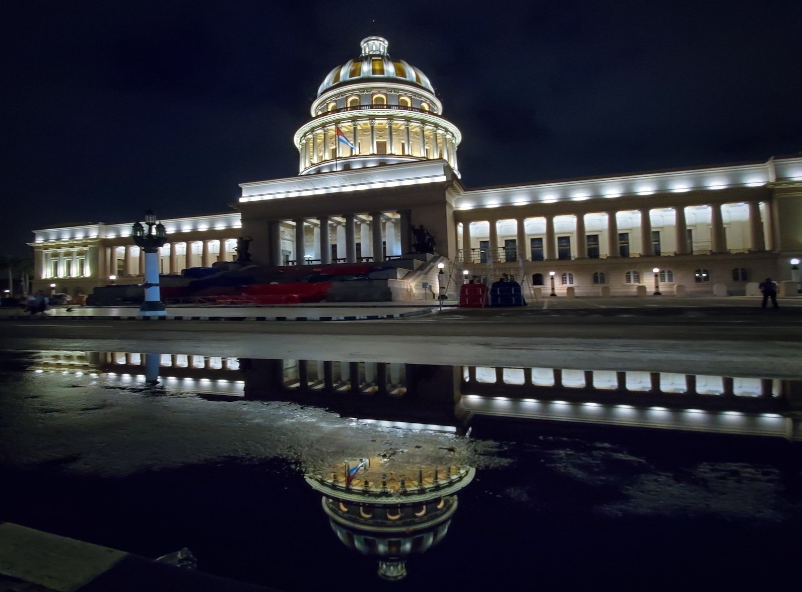 Cuban capital building lit up at night with the cupula reflected in water below