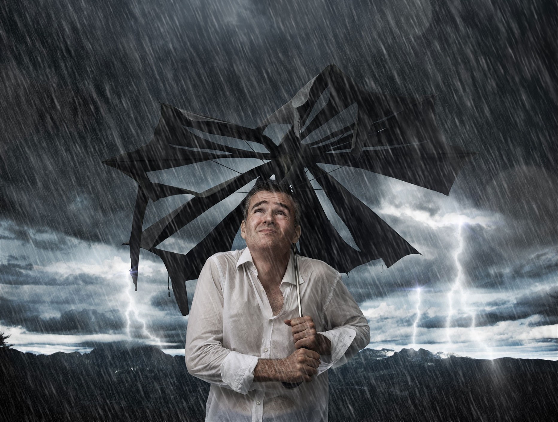 hombre sujetando un paraguas triturado durante una tormenta