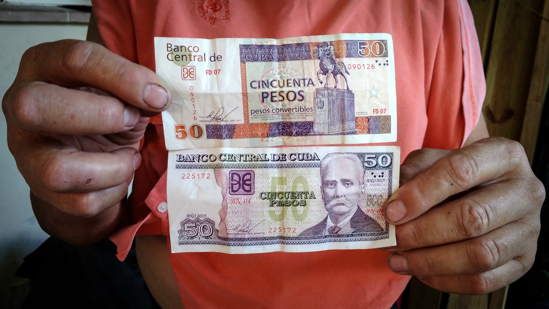 Foto: OnCuba News mano aguanto billetes respresentando dos monedas cubanas