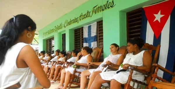 mujeres embarazadas en mecedoras con fondo verde y bandera cubana
