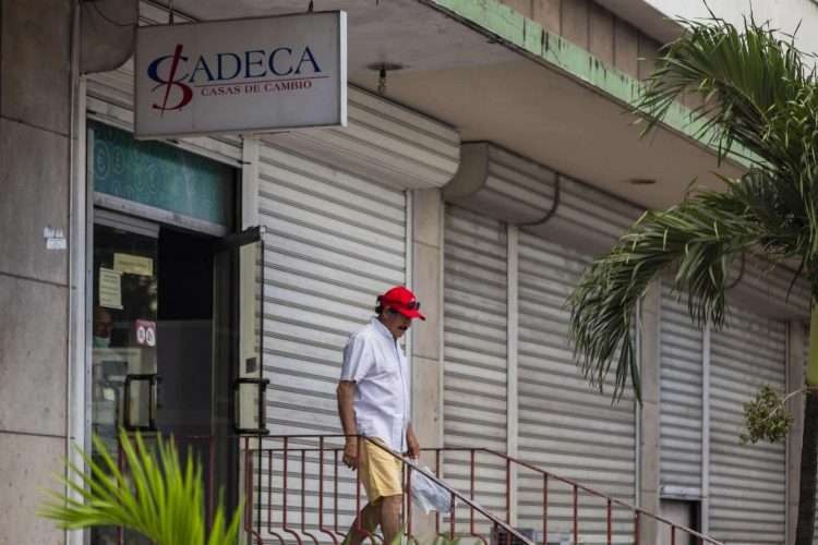 hombre con shorts amarillo y boina roja saliendo de una oficina de CADECA