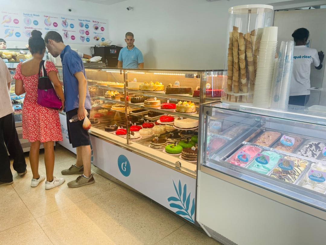 heladeria moderna vendiendo panes, helados, y dulces con persona vestida de rojo a la izquierda