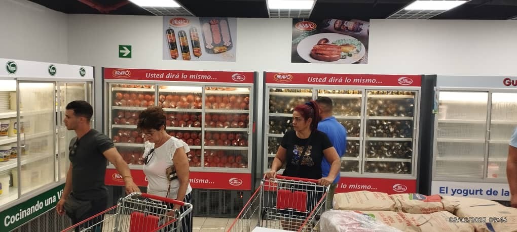 productos en estantes refrigerados con varias personas llevando carritos y comprando 