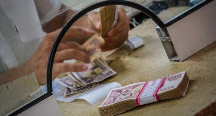 hands exchanging bills at bank window