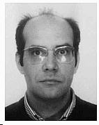 Man with a receding hairline wearing glasses and looking directly at the camera