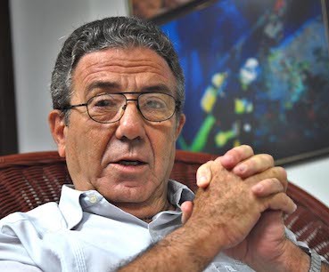 Miguel Alejandro Figueras Pérez imagen de hombre con lentes sentado con manos enlazadas