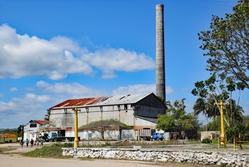 Collapsing sugar processing plant with blue sky and white clouds