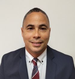 Reynaldo Senra Hodelin hombre con pelo corto negro, camisa blanca y saco y corbata