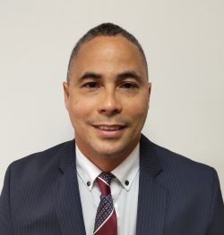 hombre con pelo corto negro, camisa blanca y saco y corbata