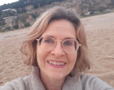 mujer de pelo castaño con lentes sonriendo