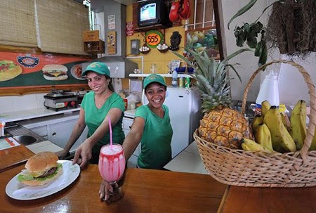 dos mujeres sonrientes vestidas de verde sirviendo comida