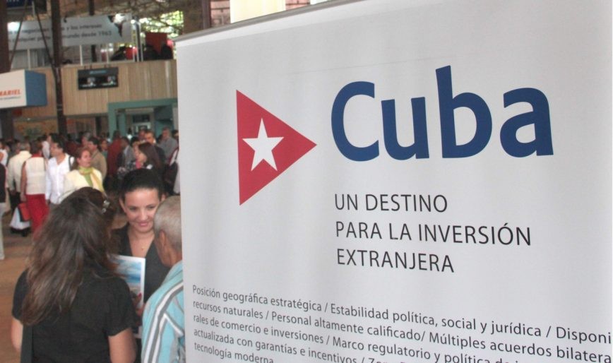 Foto: Procuba.cu afiche sobre inversión en Cuba letras azules sobre fondo blanco y triangulo rojo con estrella blanca