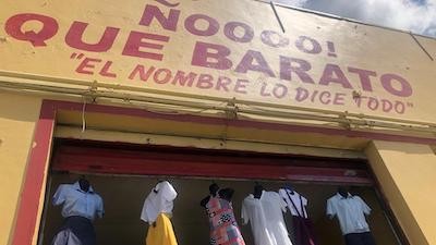 store front with yellow background and red letters and clothing hanging in the air