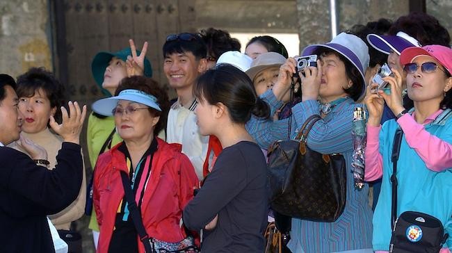 Chinese tourists in Cuba with cameras and one holding up fingers in V sign