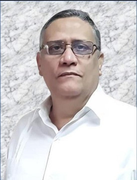 A close-up portrait of a middle-aged man wearing dark-rimmed glasses. He is wearing a formal white shirt and looking directly at the camera with a serene expression. The background features a texture simulating marble in light and gray tones.