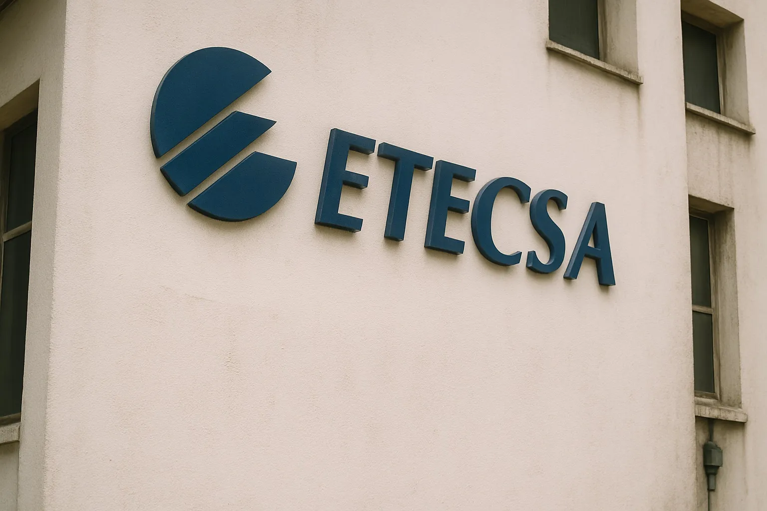 Digital photograph of a building with the logo of the Cuban telecommunications company ETECSA affixed to one of its walls. The image features a side angle that emphasizes the logo's three-dimensional letters on a light-colored wall.