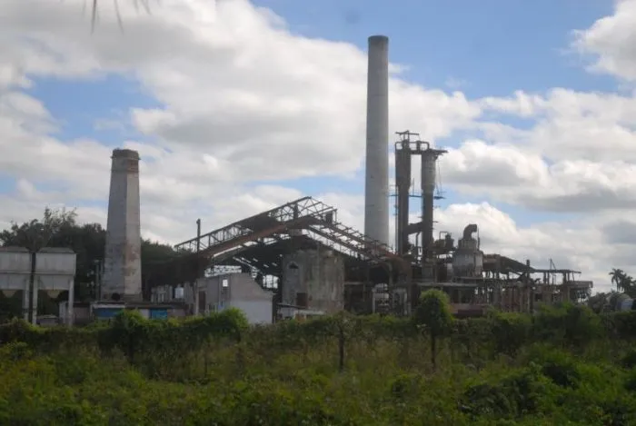 La imagen muestra una antigua planta industrial en ruinas, con estructuras oxidadas y vegetación creciendo a su alrededor. Transmite una sensación de abandono y del fin de una era productiva.