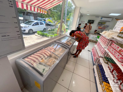 Foto: OnCuba News | Negocio privado de comida mujer vestida de rojo examinando un mostrador de comida