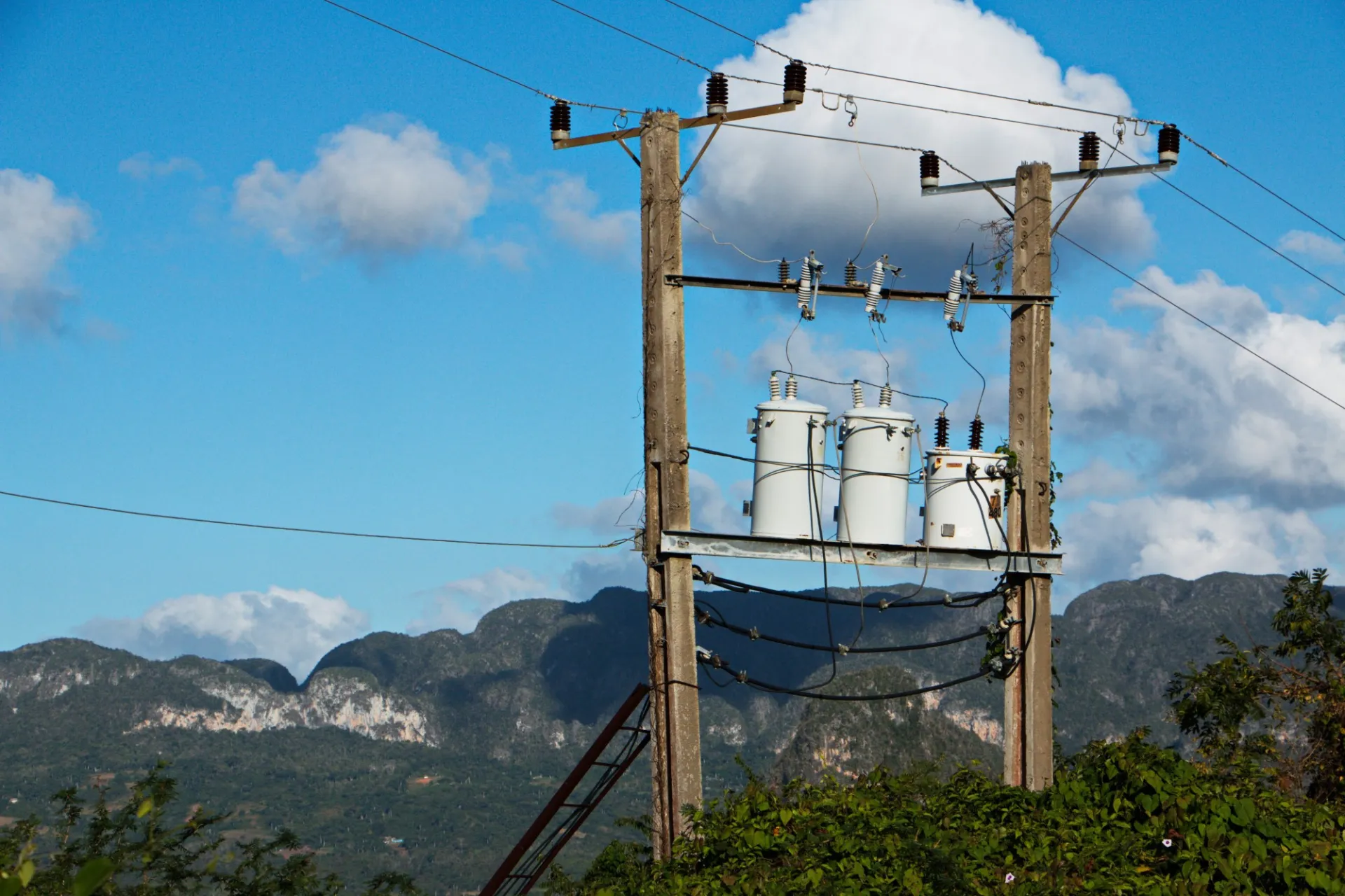 Tres contenedores de metal en una estructura de madera con fondo de cielo azul y nubes blancas