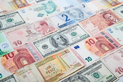 billetes de varias denominaciones, países y colores repartidos en una mesa