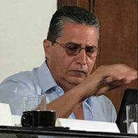 hombre con lentes y camisa azul subiendo la mano 