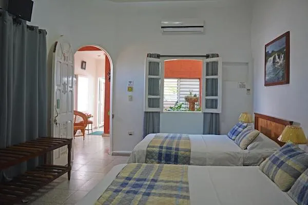 Cuarto de hospedaje con dos camas y ventanas abiertas a un salón