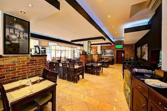 el interior un restaurante con sillas de madera altas y oscuras, detalles de ladrillos y bufet a la derecha
