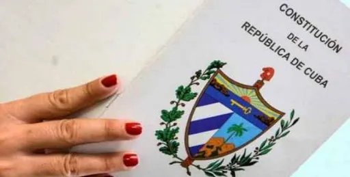 mano con uñas pintadas rojo sobre un panfleto blanco con el escudo de cuba