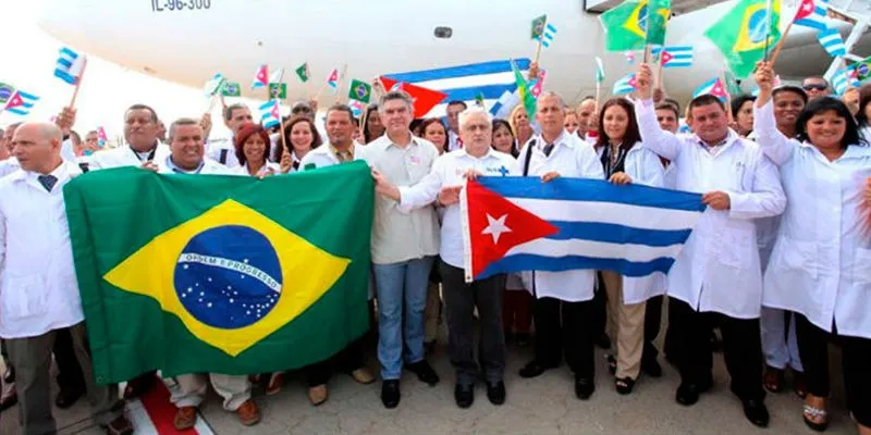 A group of Cuban doctors dressed in white, holding the Cuban and Brazilian flags