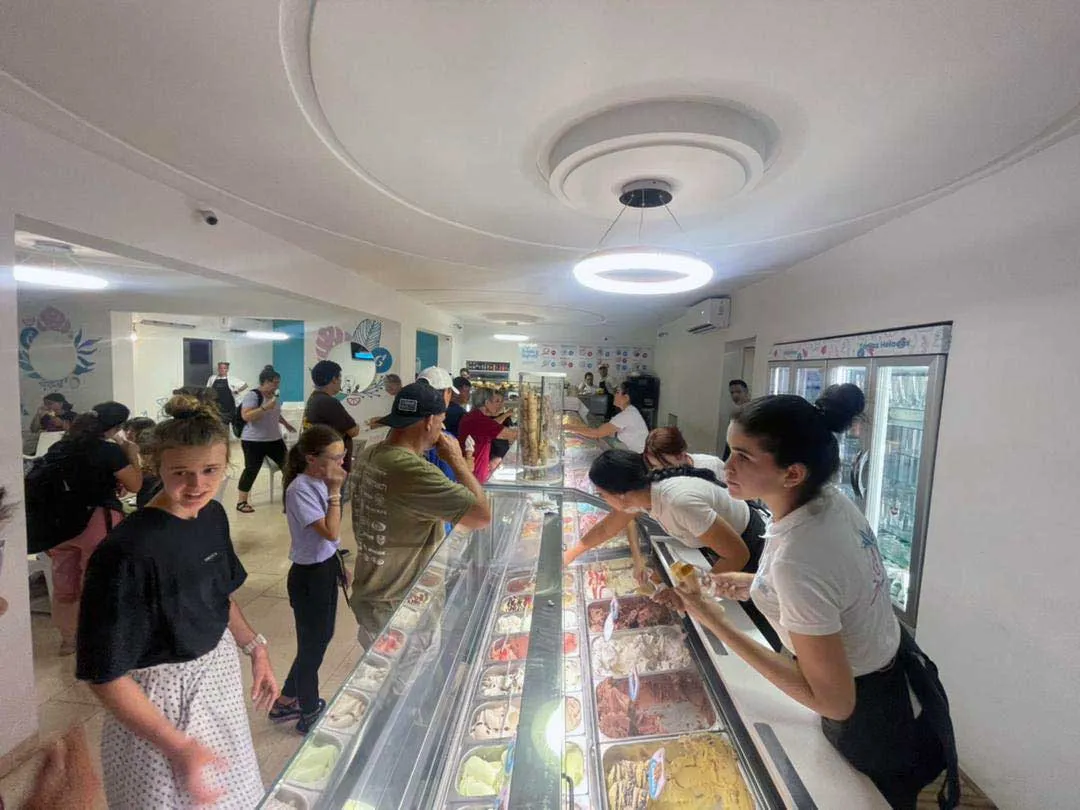 mujer vestida de blanco y negro sirviendo helado en frente de un mostrador
