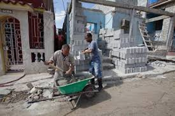 dos hombres con carrito verde trabajando en construcción