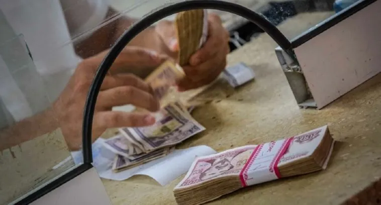 manos cambiando billetes en casilla bancaria