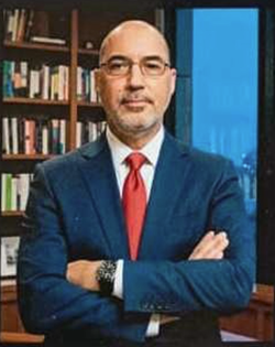 Man wearing a blue suit and red tie crossing his arms and looking directly at the camera