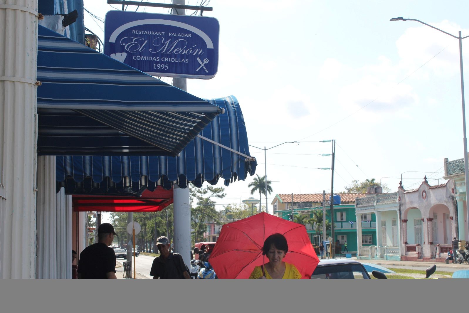 cartel en azul y blanco con titulo "El Mesón" y mujer con paraguas rojo