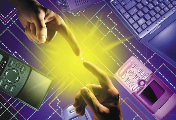 two fingers pointing to each other with computers in background